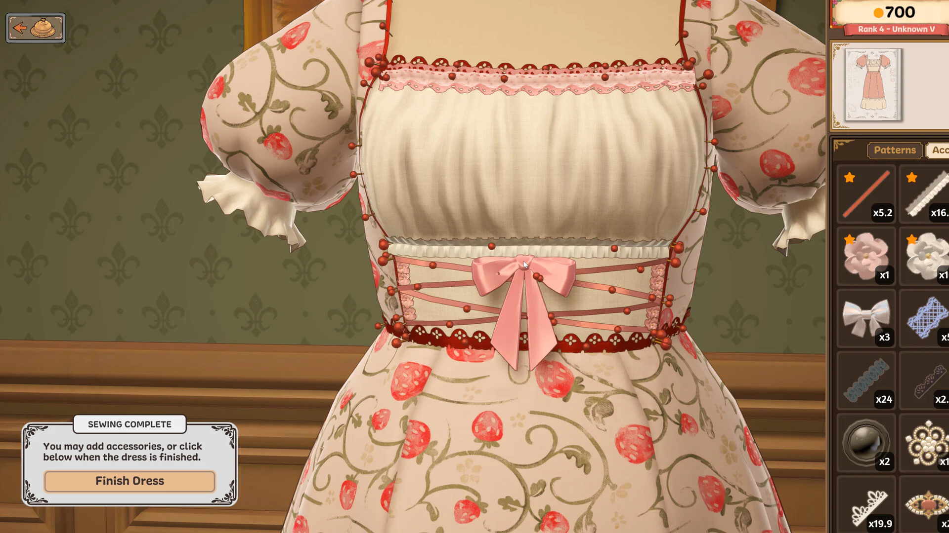 Close view of a strawberry-print dress decorated with lace, ribbon, flowers, and a pink bow in Dressmaker